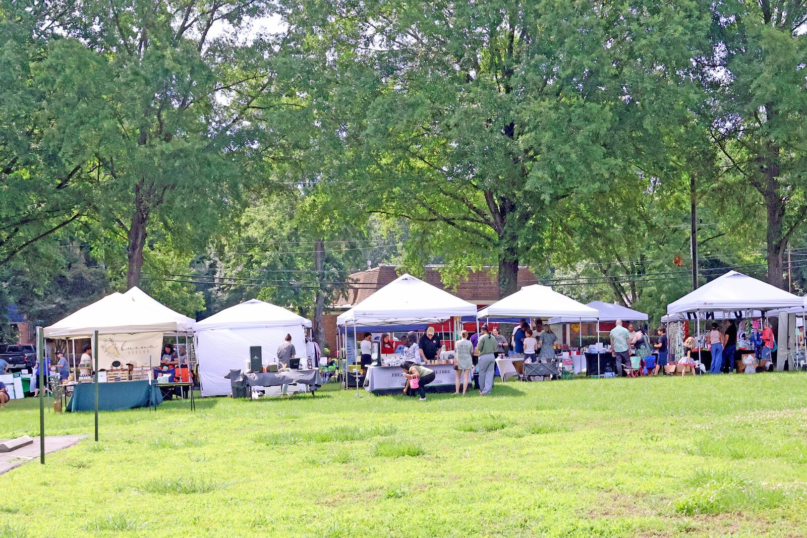 White vendor tents on a green lawn at the pop-up market
