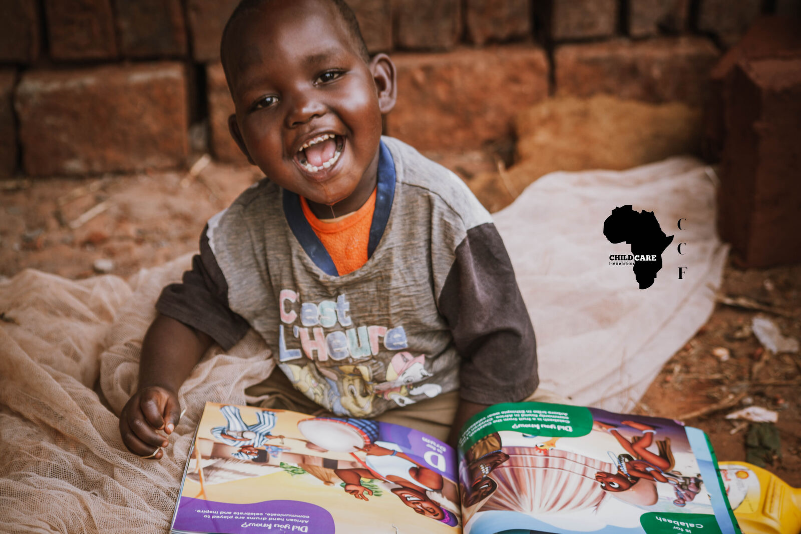 Laughing child reading a donated book in Uganda
