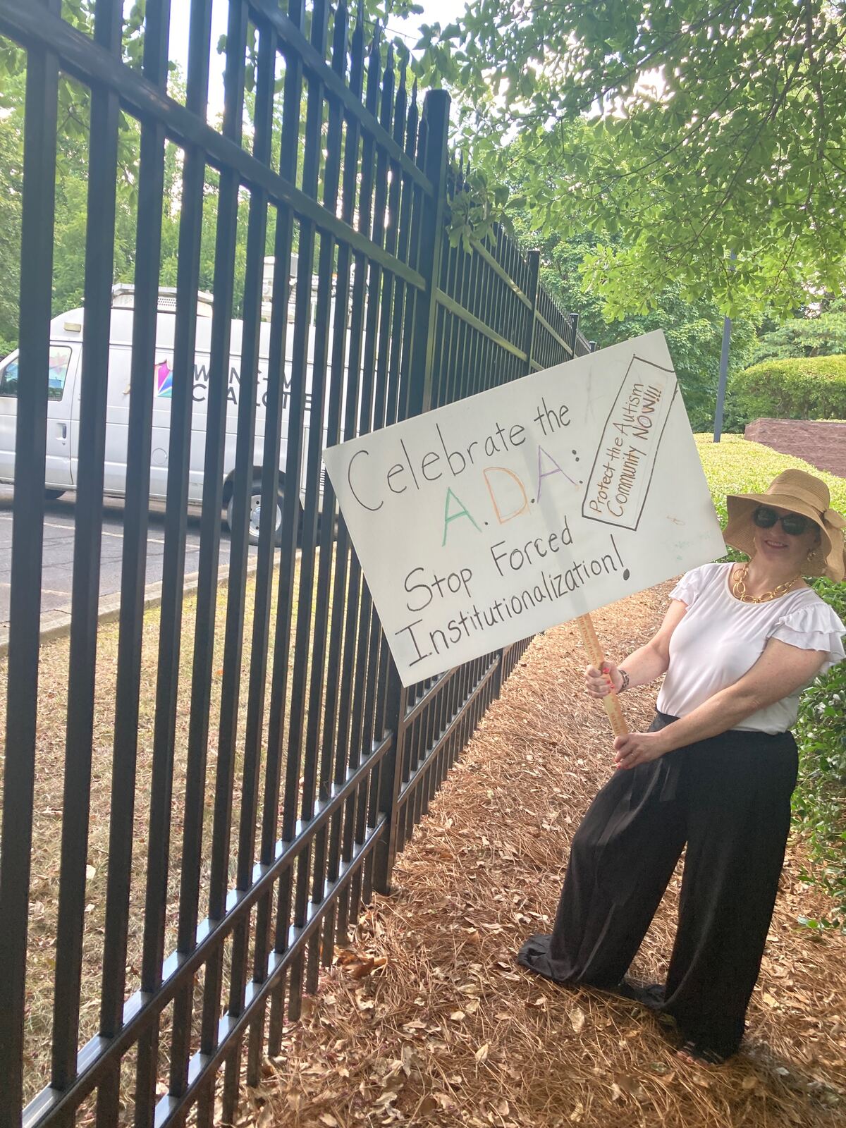 Advocate holding a sign reading Celebrate the ADA, stop forced institutionalization