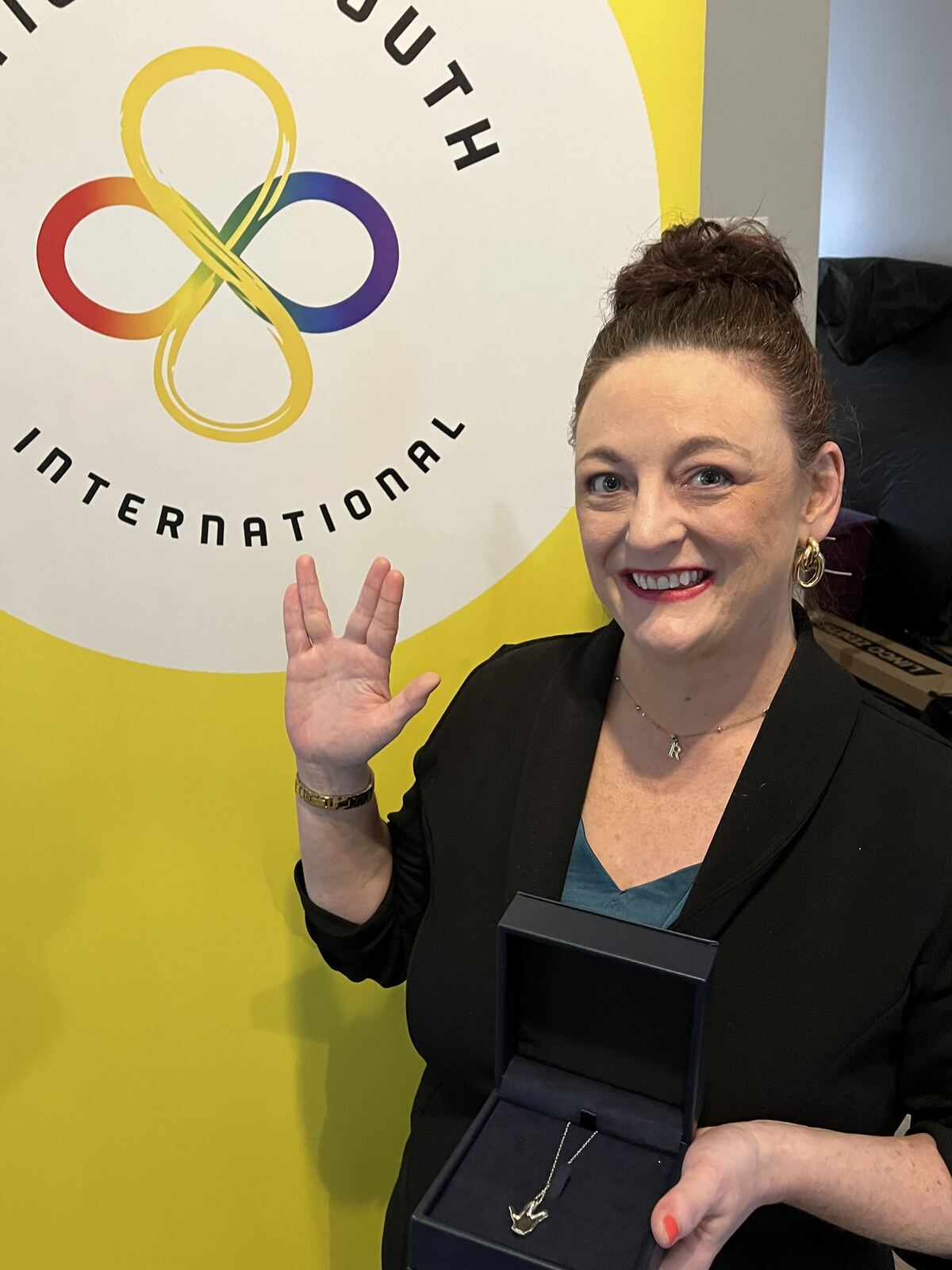 Founder Rebecca Tarrant in front of the Autistic Youth International logo