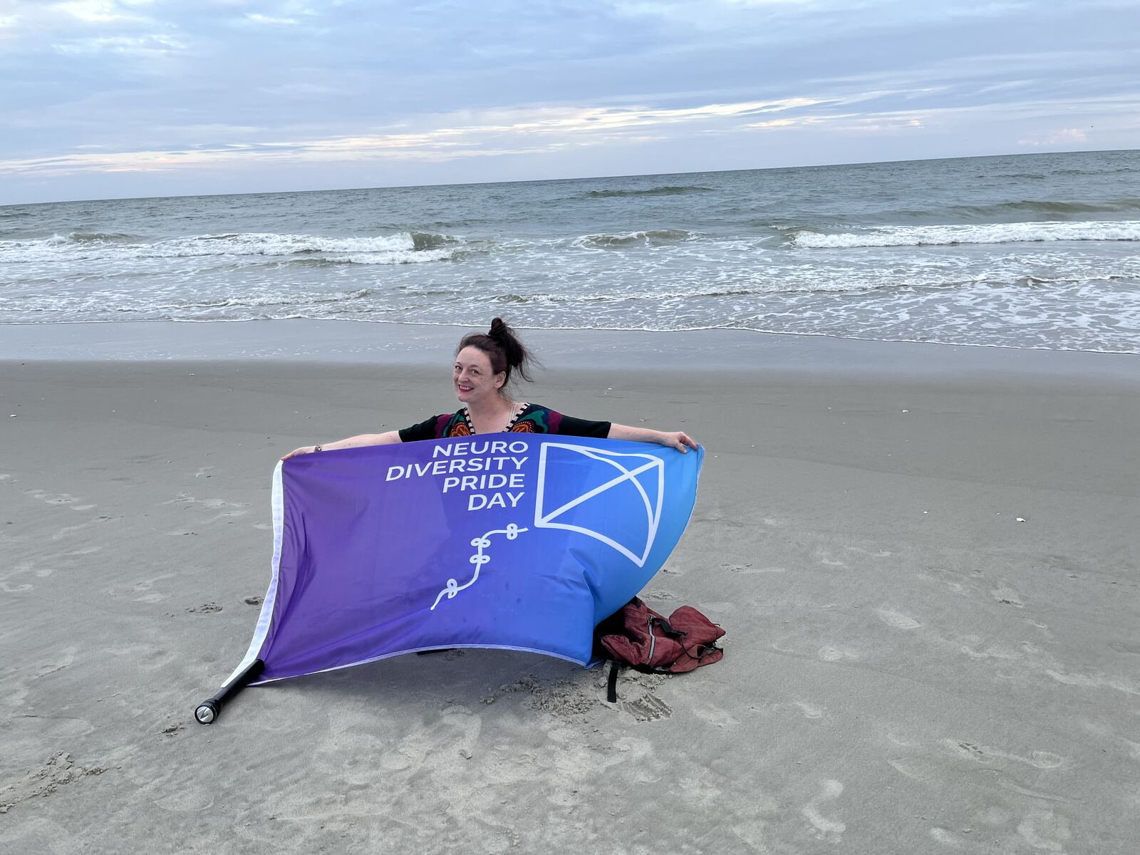 Neurodiversity Pride Day flag held up on a beach